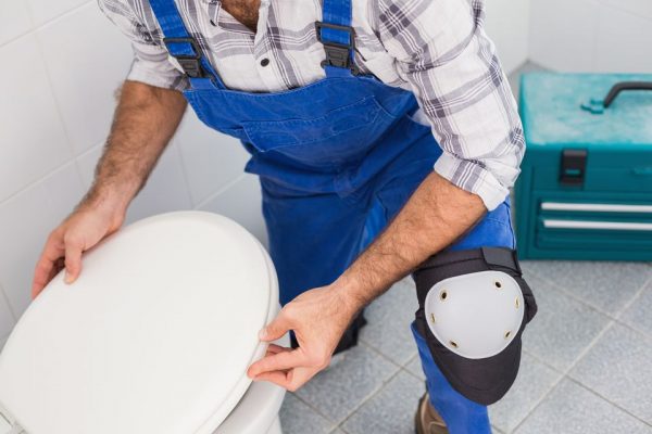 a handyman installing a toilet bowl in the bathroom