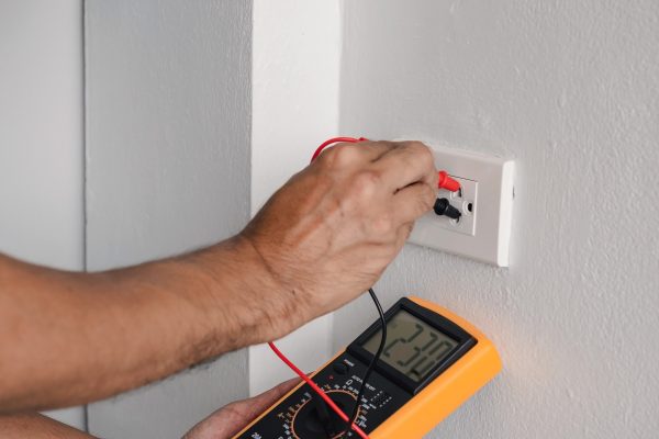 an electrician using a digital meter to check the voltage of an outlet