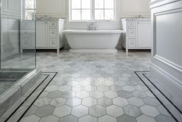 a simple bathroom with a tub, shower and hexagonal grey and white tiles