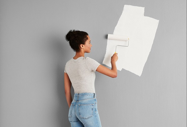 A woman painting the wall with a paint roller