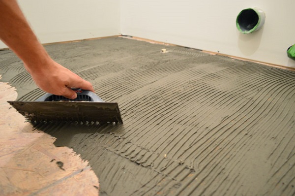 A hand applying cement to the floor